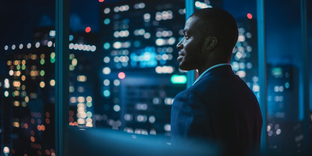 Man looking out an office window at night.