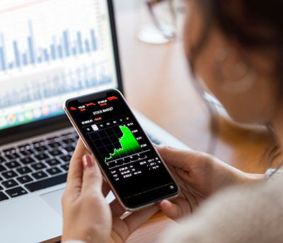 A person looks at a smartphone showing a graph.